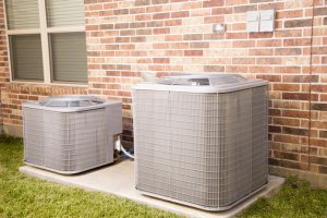 Two air conditioner units outside brick home. Service industry, construction industries.