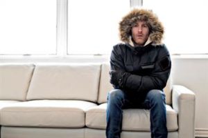 Man wearing winter jacket seating on a sofa