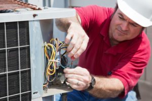Air conditioning repairman rewiring a compressor unit