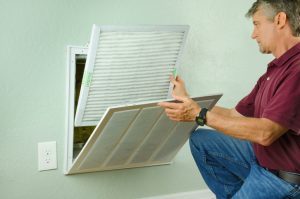 Professional repair service man or diy home owner installing a clean new air filter on a house air conditioner which is an important part of preventive maintenance.