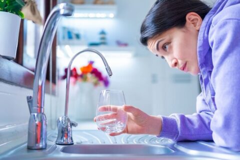 The girl filling water in glass from tap