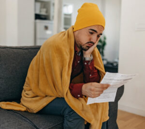 Cold & Upset Man sitting on a sofa with a Heating bill