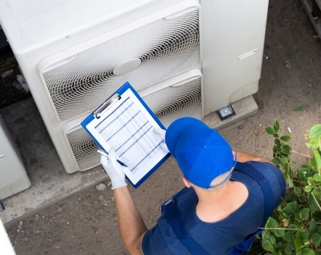 A man overalls examines a heat pump and provides HVAC maintenance tips in Provo and Orem, UT.
