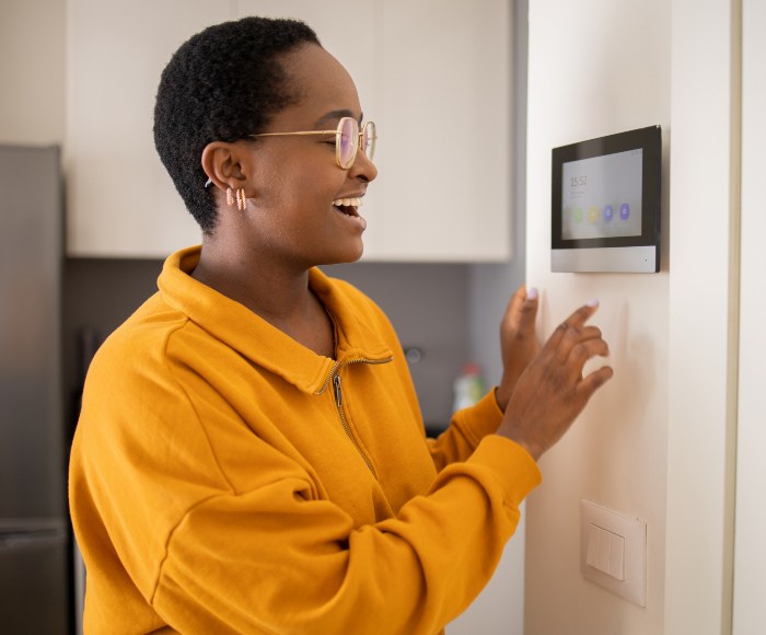Young woman adjusts the temperature at home with smart thermostat